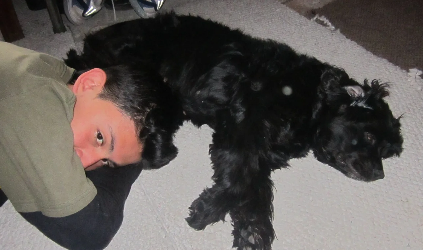 Eduard abrazado a Natacha, una cocker spaniel negra, acostados en el piso
